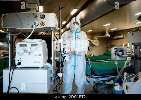 Un medico che indossa un tuta per dispositivi di protezione individuale (PPE) visto vicino ad un ventilatore respiratorio. In mezzo alla seconda ondata dell'emergenza Covid-19, l'esercito italiano ha assemblato un ospedale da campo nel cantiere navale di vaglio Lise come unità esterna dell'Ospedale S. Annunziata a Cosenza. Composto da 18 unità, l'ospedale da campo ospita 3 posti per le persone che necessitano di terapia sub-intensiva, unità con 40 posti letto per i pazienti affetti da Covid-19, un'unità di radiologia, una farmacia e un laboratorio per l'elaborazione del test diagnostico molecolare (test con tampone). Foto Stock