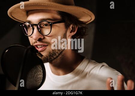 Ritratto di cantante maschile di stile che registra una nuova canzone in studio moderno. Bel musicista che canta in studio sonoro Foto Stock