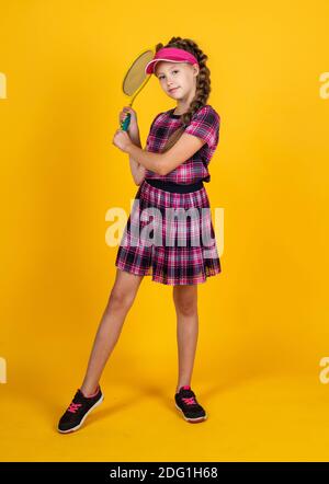 felice ragazza con attrezzatura sportiva. racchetta da tennis per bambini. bambino con cuffia fitness. attività infantile. stile di vita sano. energia. giocatore di badminton con racchetta. Foto Stock