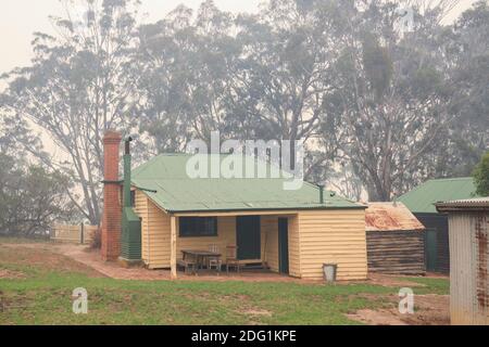 Vecchio edificio agricolo nel Nyerimilang Heritage Park avvolta nel fumo durante i fuochi d'arresto a Gippsland Est, Victoria, Australia Foto Stock