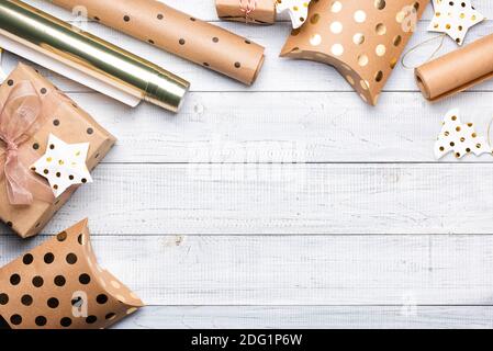 Scatole regalo di Natale e carta da imballaggio in colori oro su sfondo di legno bianco. Copiare spazio per il testo. Disposizione piatta e vista dall'alto Foto Stock