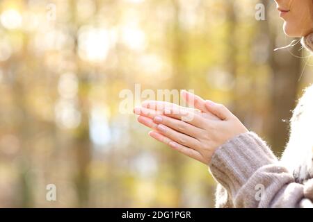 Primo piano di donna sfregamento e calore mani in un autunno freddo in un parco Foto Stock