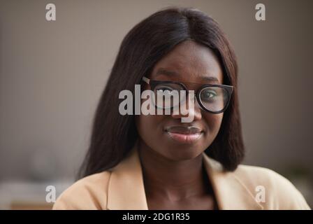Primo piano ritratto di giovane donna d'affari afroamericana indossando occhiali e sorridendo a macchina fotografica, copia spazio Foto Stock