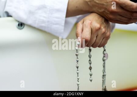 Dettagli con le mani di una suora cattolica che tiene un rosario. Foto Stock