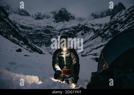 Man Making Tea vicino alla tenda in Svizzera Montagne Inverno Foto Stock