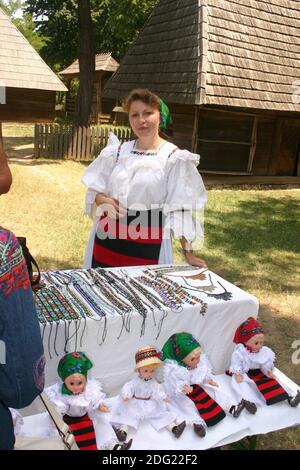 Donna di Maramures, Romania, che vende gioielli fatti a mano in perline e bambole souvenir Foto Stock