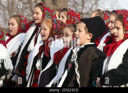 Gruppo di giovani carolieri rumeni in costumi tradizionali che cantano per Un evento di Natale Foto Stock