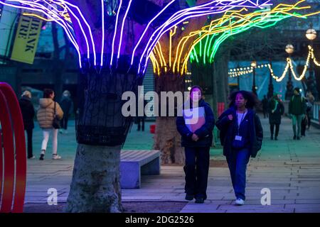 Londra, Regno Unito. 7 dicembre 2020. I membri del pass pubblico accanto a 'Lumen' di David Ogle, alberi illuminati con riflessi al neon. Anteprima di "Winter Light" presentata da Southbank Centre. Oltre 15 opere d'arte e nuove commissioni illuminate da una serie di artisti internazionali sono in mostra intorno agli edifici del sito e al Riverside Walk fino alla fine di febbraio 2021. Credit: Stephen Chung / Alamy Live News Foto Stock