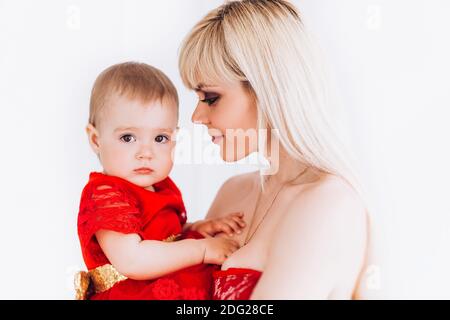 Bella, famiglia, buona foto di madre e figlia in abiti rossi in studio. Festa della mamma e figlie. Pubblicità dei valori e delle tradizioni familiari. Foto Stock
