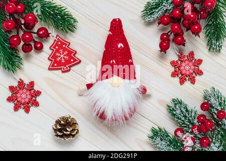 Sfondo di Natale su tavole di legno chiaro. Gnomo giocattolo in un cappello a forma di cono rosso, Babbo Natale con una barba bianca. Decorazioni per le vacanze. Fiocchi di neve e f Foto Stock