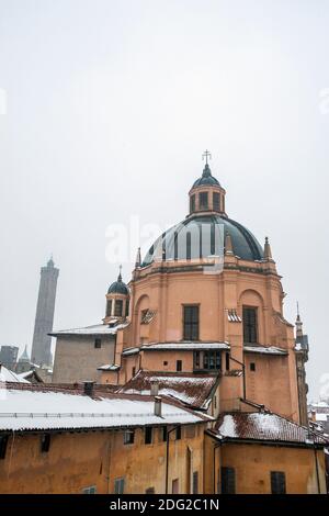 Neve che cade sulla chiesa e sui tetti di Santa Maria della vita, Bologna, Italia, e le torri pendenti di Garisenda e degli Asinelli. Foto Stock