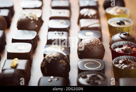 Tartufi di cioccolato fondente e al latte di lusso. Deliziose praline di cioccolato fatte a mano assortite in fila. Sfondo a cornice intera. Scatto studio. Primo piano. Foto Stock