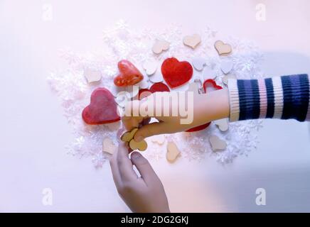 Piccoli cuori colorati nelle mani del bambino. Processo di decorazione del regalo. Foto Stock