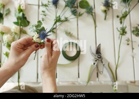 Donna fiorista mani raccoglie i fiori per lo sposo boutonniere. Evento decorazione fiori freschi. Flusso di lavoro fiorista. Design per banchetti di nozze. Foto Stock