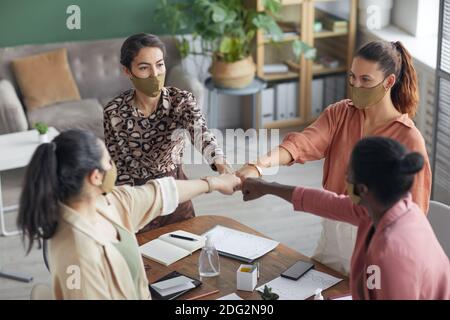 Ritratto ad alto angolo alla squadra di affari femminile che si accoccolano e si battono i pugni mentre festeggia il successo alla riunione, copy space Foto Stock