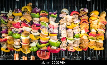 Chef cucina uno spiedini deliziosi sulla griglia barbecue. Cuocete la brochette sulla carne alla griglia. Cibo cucinato con barbecue grigliato nel cortile della casa Foto Stock