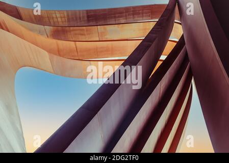 Architettura urbana futuristica. Triangoli verticali ad arco d'arte realizzati in metallo di stagno marrone con sfondo blu. Sfondo astratto. Messa a fuoco selettiva Foto Stock