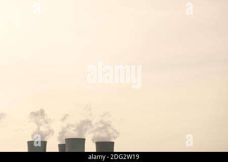 Cime di quattro camini di centrale nucleare in tonalità seppia con spazio di copia. Produzione di energia elettrica. Fumo industriale Foto Stock