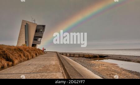 Rainbow at Rossall Beach, Fleetwood, Lancashire, Regno Unito. L'edificio a quattro piani sul lungomare esterno di Rossall Point e' la Torre dell'Orologio costiero di Rossall. Foto Stock