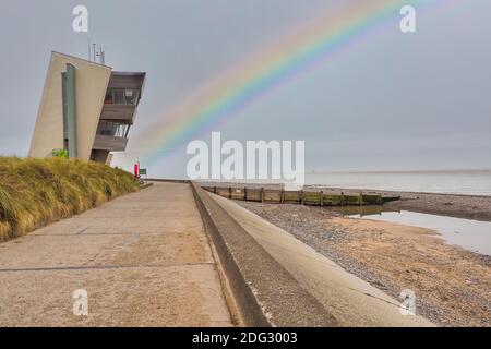 Rainbow at Rossall Beach, Fleetwood, Lancashire, Regno Unito. L'edificio a quattro piani sul lungomare esterno di Rossall Point e' la Torre dell'Orologio costiero di Rossall. Foto Stock