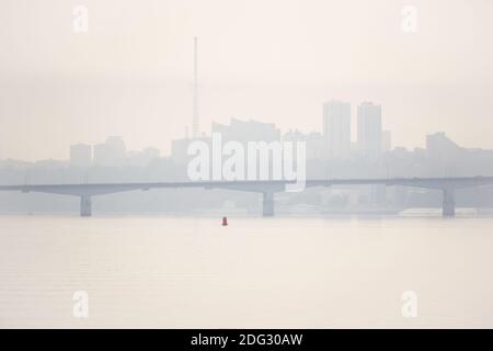 ponte stradale su un ampio fiume e la sagoma di una città lontana dietro di essa nella tormentata del mattino Foto Stock