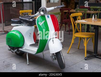 Una moto Vespa in colori italiani fuori da un ristorante in piazza Leicester. Londra Foto Stock