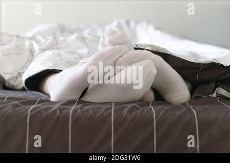 Coppia in calze bianche sdraiata nel letto. Gli amanti insieme al mattino. Foto Stock