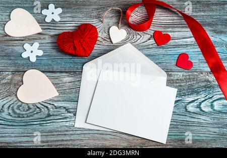 Busta, cuori e nastro su sfondo grigio-blu di legno. Foto Stock