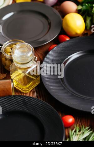 piatti neri su sfondo di legno con verdure e frutta disposto Foto Stock