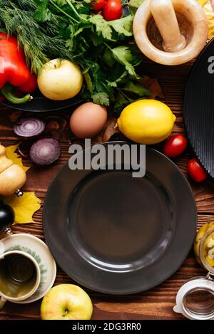 piatti neri su sfondo di legno con verdure e frutta disposto Foto Stock