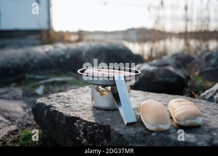 Cucina a fuoco all'aperto sulla spiaggia al tramonto in Svezia Foto Stock