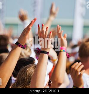 Folla di persone che alzano le mani per rallegrarsi Foto Stock