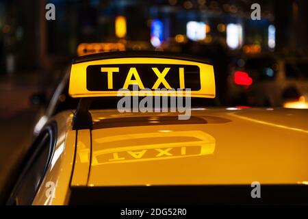 Segnale taxi illuminato sul tetto di un taxi di notte Foto Stock
