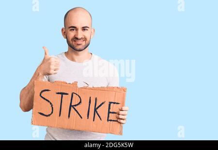 Giovane bell'uomo che tiene bandiera di colpo sorridente felice e positivo, pollice su facendo eccellente e segno di approvazione Foto Stock