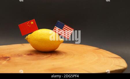 Bandiere americane e cinesi che si stancano di un limone su un blocco di trinciatura che rappresenta la relazione souled tesa e. la guerra commerciale è stata condotta tra Foto Stock