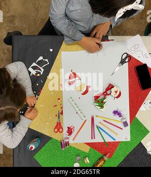 Vista dall'alto di una madre e di una figlia che fanno artigianato mentre disegnandoli e incollandoli su cartone colorato a casa Table.on uno sfondo di cartbo colorato Foto Stock