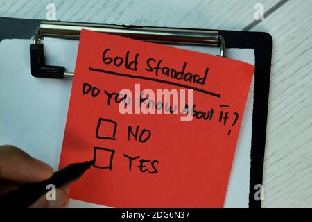 Gold Standard scrivere su note appiccicose e supportato da servizi aggiuntivi isolati su tavolo in legno. Foto Stock