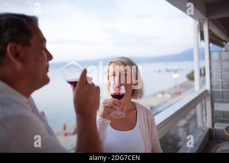 Paio di bere il vino rosso sul balcone del Beach Hotel Foto Stock