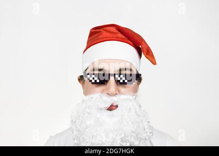 Babbo Natale in divertenti occhiali da sole pixelati su sfondo bianco. Gangster, boss, meme di vita del delinquere. stile a 8 bit. Holly Jolly x Mas Noel. Freddo Foto Stock