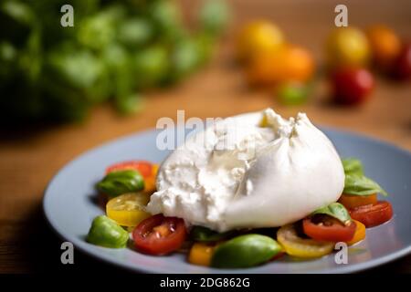 Burrata su insalata colorata di pomodoro e basilico Foto Stock