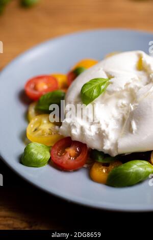 Burrata su insalata colorata di pomodoro e basilico Foto Stock