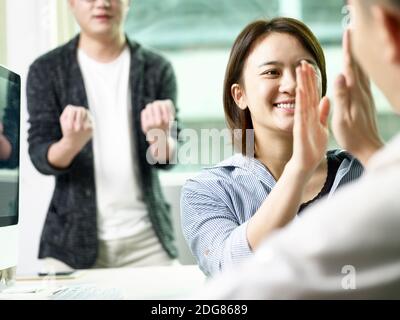 squadra di tre uomini d'affari asiatici che danno un his-five che festeggia il successo e il successo in ufficio Foto Stock