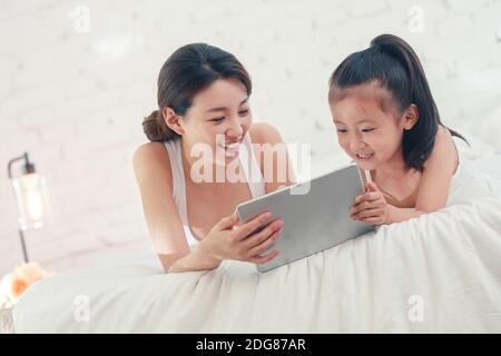 Felice madre e figlia che gioca al tablet Foto Stock