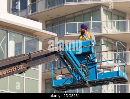 Operatore di costruzione in piedi nella benna della gru mobile. White Rock, British Columbia/Canada, ottobre 22,2020. Messa a fuoco selettiva, foto di strada. Foto Stock