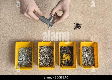 Scatole di plastica con le viti e le mani maschio Foto Stock