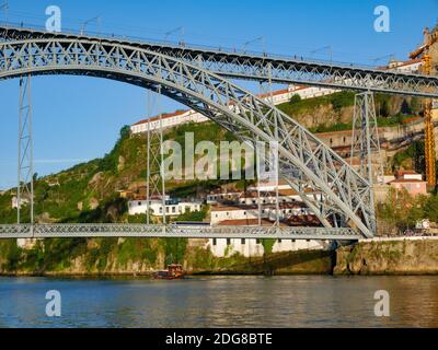 Foto a basso angolo del Ponte Luis a Porto come una barca di rabelo passa sotto Foto Stock