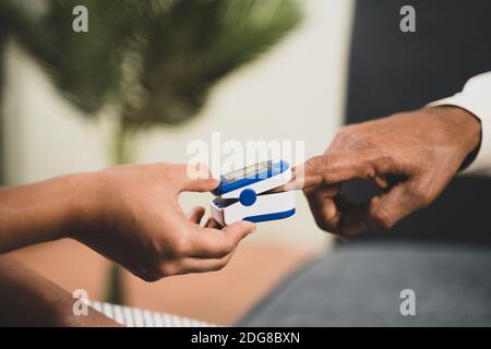 Primo piano delle mani del medico che controlla la temperatura dei malati anziani uomo che usa un termometro a infrarossi in ospedale mentre entrambi indossano il viso maschera a causa del coronavirus covi Foto Stock