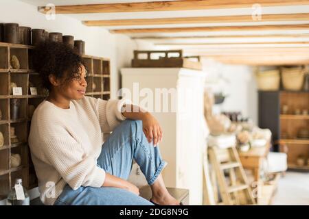 Pensieroso proprietario di negozio femminile che guarda via Foto Stock