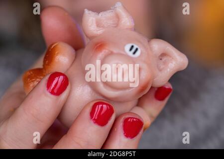 Tenendo un piccolo maiale marzapane rosa per mangiarlo Foto Stock