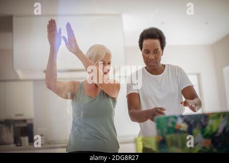 Le donne anziane amici che si esercitano in linea al laptop in cucina Foto Stock